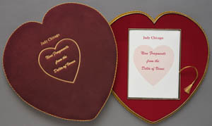 Lid and bottom of a dark red heart-shaped box with gold trim and printed paper inside
