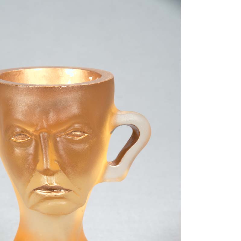 Mug in translucent gold with a face, handle, and a flared base
