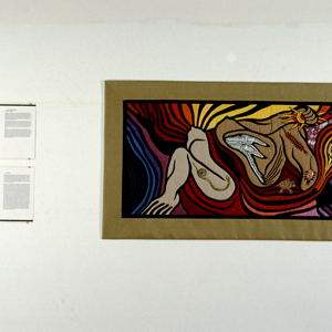 Color photograph of a colorful artwork with abstracted female figures hanging on a wall next to black and white text panels