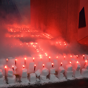 Color photograph of rows of white blocks of dry ice studded with red flares glowing and emanating fog