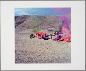 Print of small figures standing amid plumes of multicolored smoke in a desert landscape