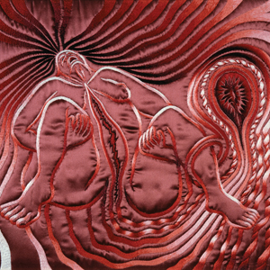 Red textile depicting a squatting woman figure with her hair flowing behind her and an embryo coming out of her vagina