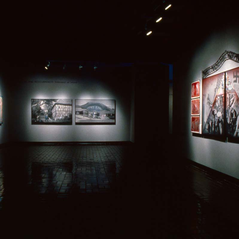Color photograph of multi-paneled artworks installed on the walls of a darkened gallery