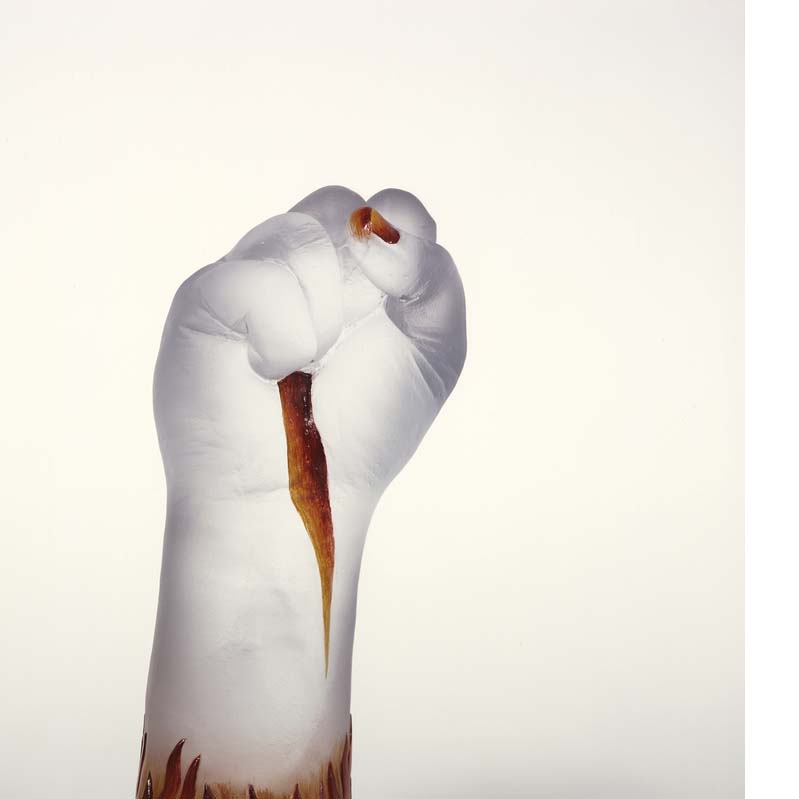 Sculpture of a translucent, raised white fist with dark brown flames at the base and on the palm