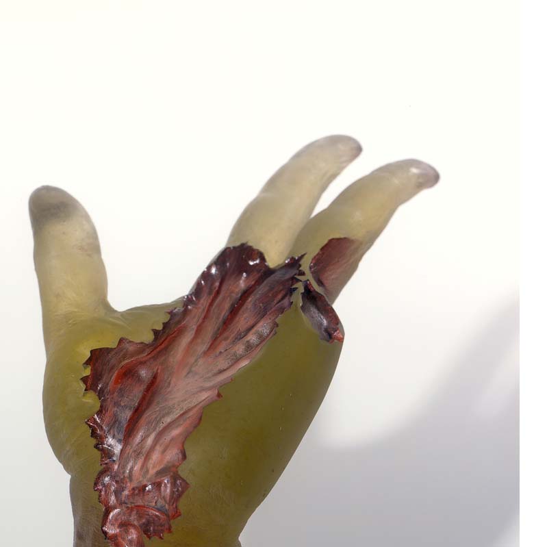Sculpture of a translucent yellow hand with two missing fingers and exposed musculature