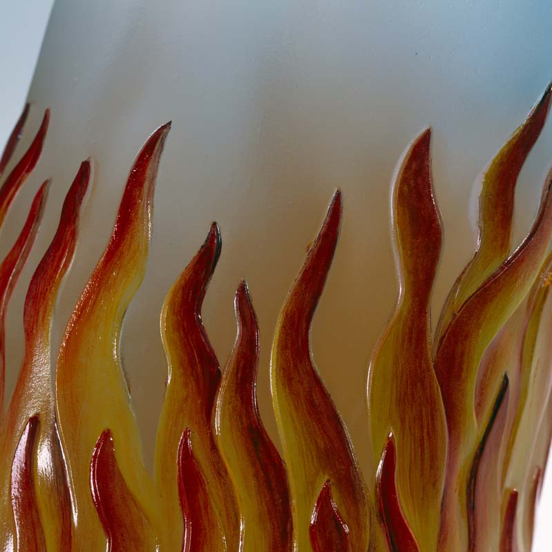 Detail of a sculpture of a translucent white arm with orange and red flames on it