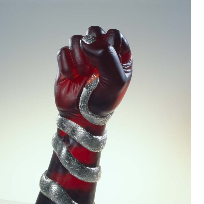 Sculpture of a translucent red raised fist with a silver snake coiled around the arm on a clear plinth