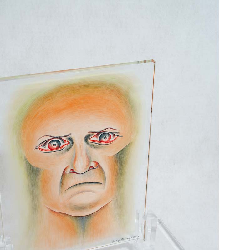 Painting on clear glass rectangle of a frowning face on a clear plinth