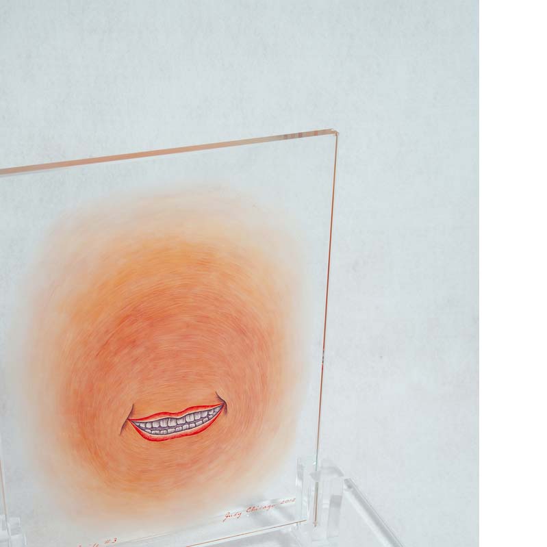 Orange, red, and brown painting of a smiling mouth on a clear glass rectangle on a clear plinth