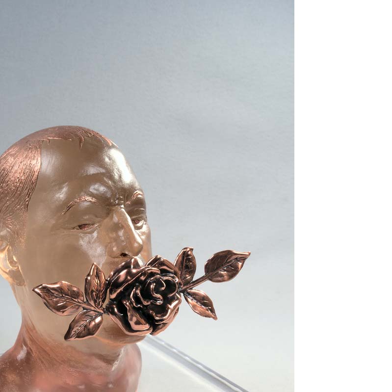 Translucent pink sculpture of a man's head with a bronze flower in his mouth on a clear plinth
