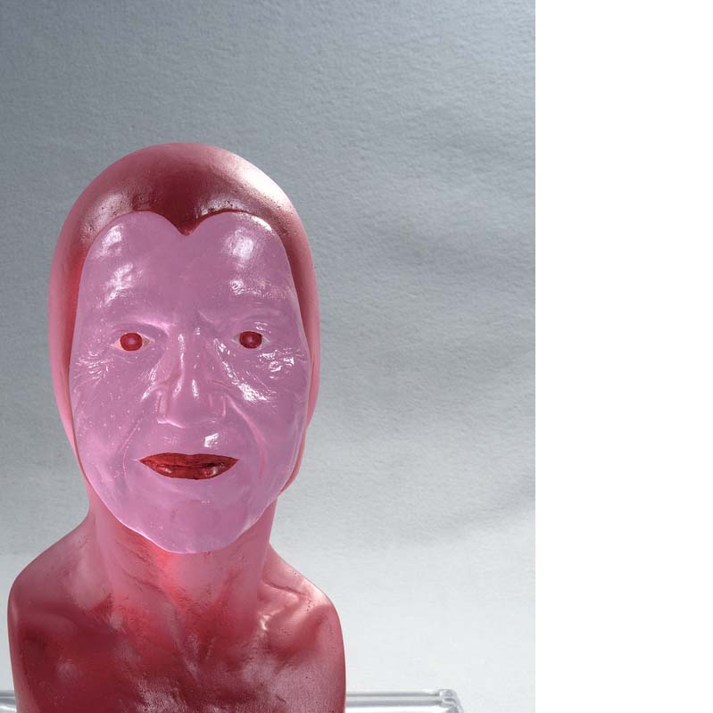 Translucent pink and red sculpture of a head wearing a bald cap or hood on a clear plinth