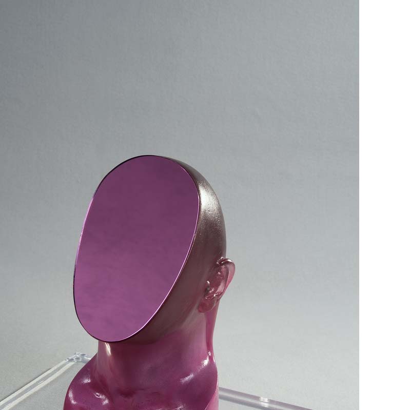 Purple sculpture of a bald head with its face sliced off on a clear plinth