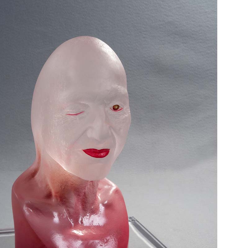 Translucent white and pink sculpture of a bald head with features painted in red on a clear plinth