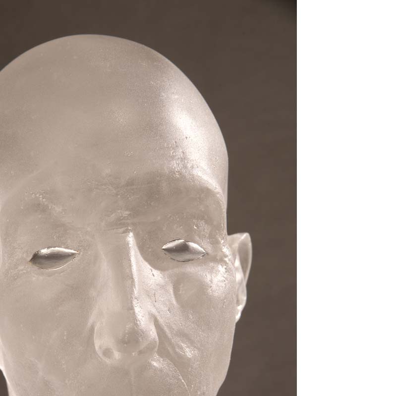 Detail of a translucent white sculpture of a bald head with silver eyes and mouth