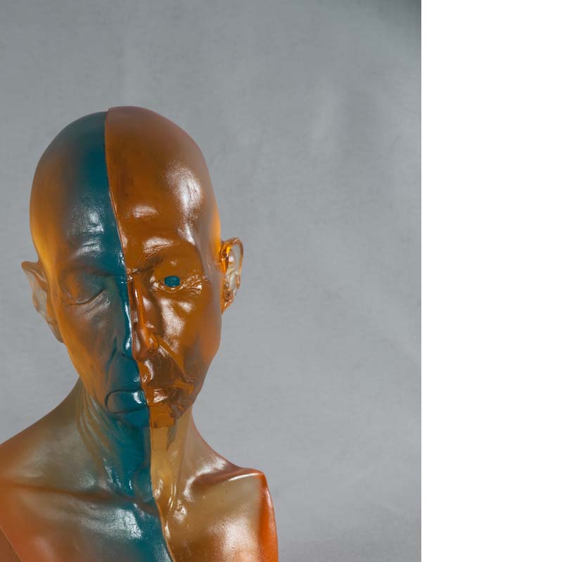 Sculpture of a bust with a bald head in translucent orange with a turquoise stripe down the center