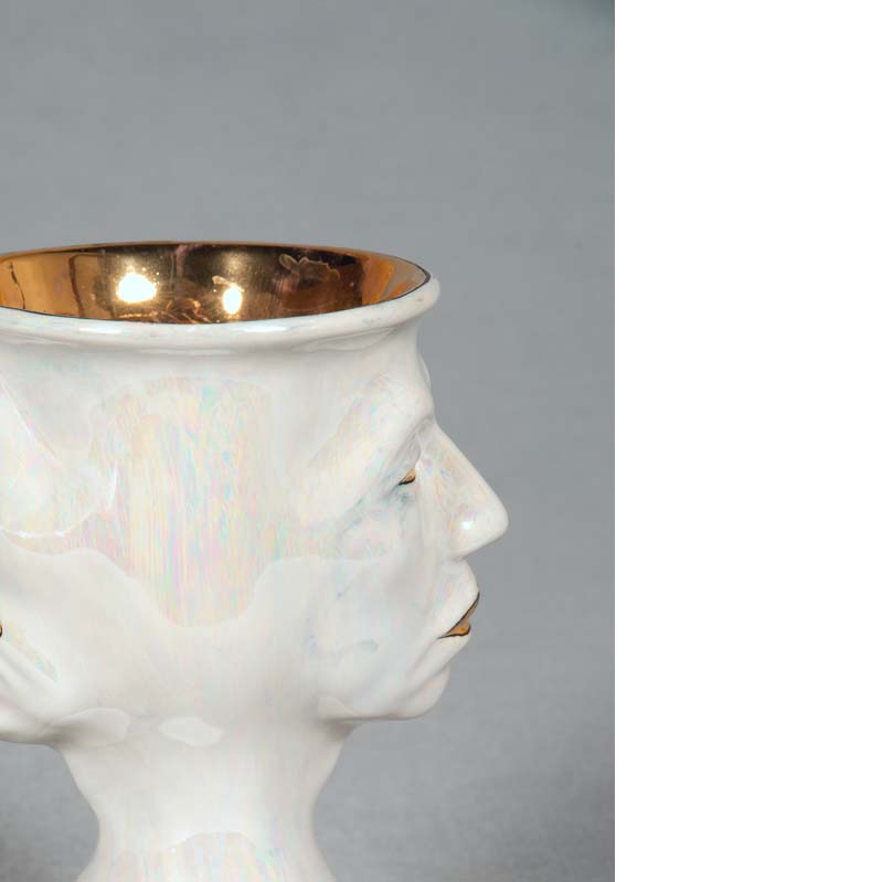 Mug in white and metallic gold with a face on either side and a flared base
