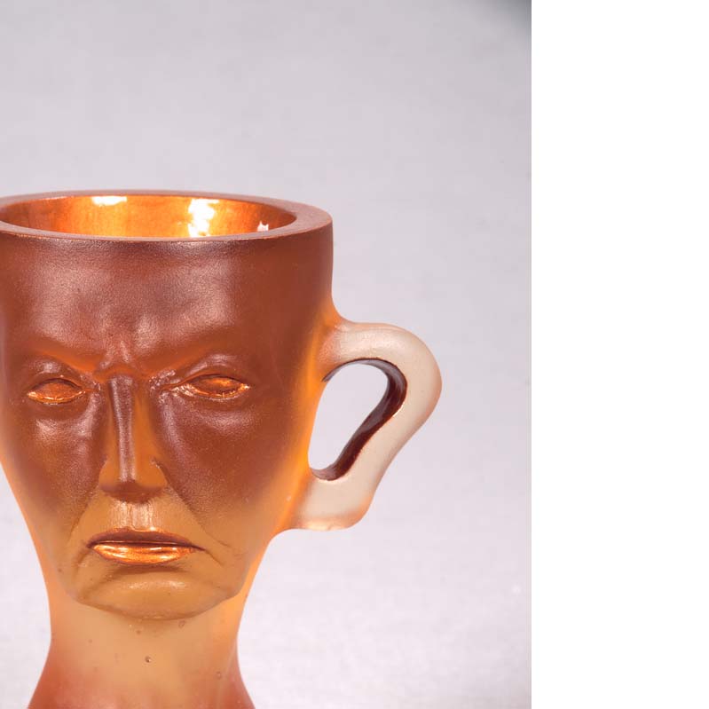 Mug in translucent orange with a face, handle, and a flared base