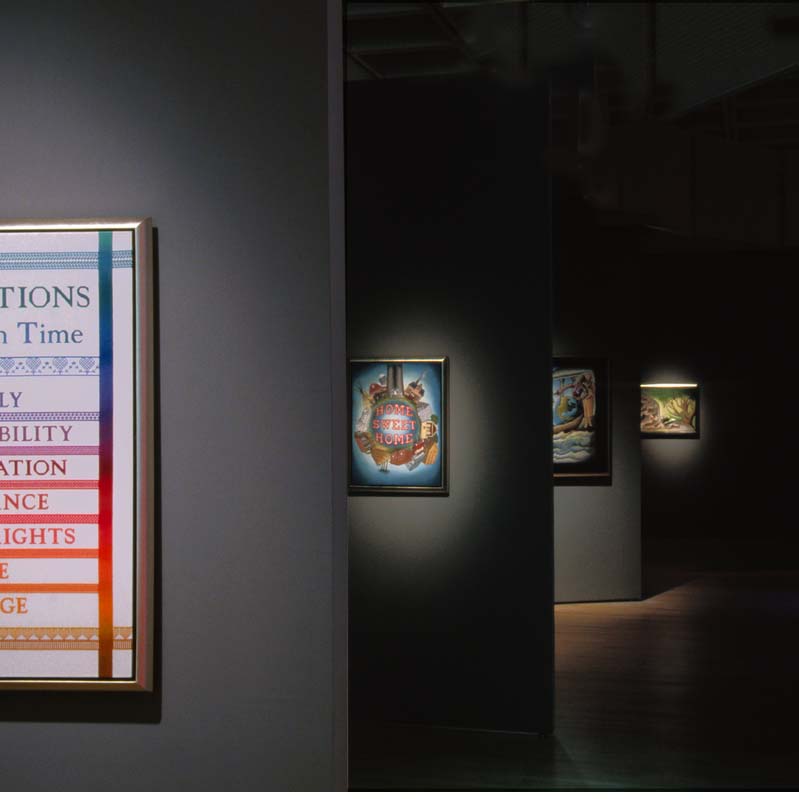 Color photograph of an art exhibition with full or partial views of five artworks on a series of gray walls
