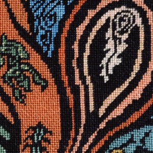 Close up of petit point artwork of organic shapes on canvas in orange, blue, and green tones