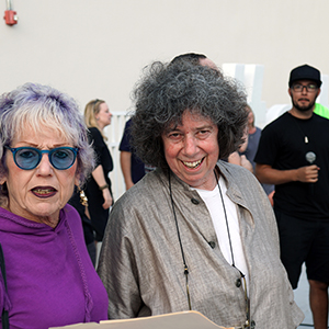 Color photograph of Judy Chicago and Diane Gelon standing outdoors with other people in the background