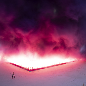 Color photograph of purple and pink smoke emerging from flares in a plaza