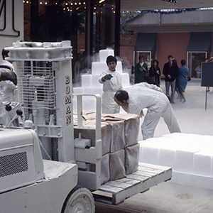 Color photograph of Judy Chicago and Lloyd Hamrol arranging dry ice blocks behind a forklift holding more blocks