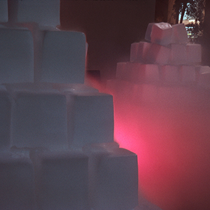 Color photograph of two pyramids of white blocks with pink smoke between them