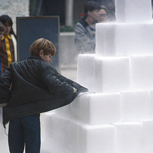 Color photograph of a young person touching a pyramid of white blocks