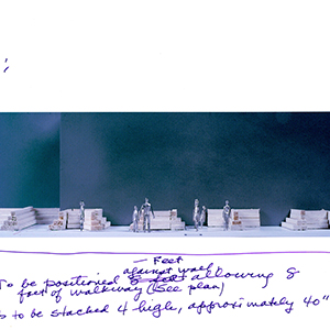 Printout with a color photograph of a model with people standing amid stepped structures, annotated with handwritten text