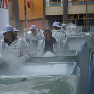 Color photograph of Mike Racine and others unloading white blocks of dry ice from bins
