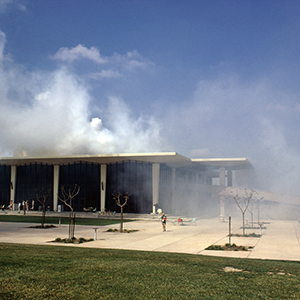 Color photograph of white smoke rising from a black and white building
