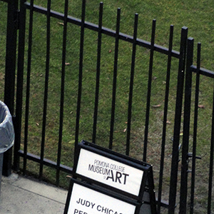 Photograph of a sandwich board sign in front of a black fence