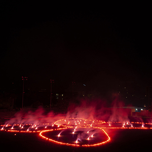 Color photograph of red flares in the shape of a butterfly on a dark ground