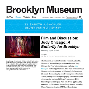 Printout of a webpage with text and a photograph of multicolored fireworks shooting up from a glowing red outline of a butterfly in a darkened park